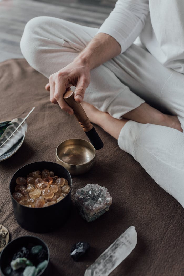 Man meditating with a singing bowl and healing crystals, capturing a serene spiritual practice.